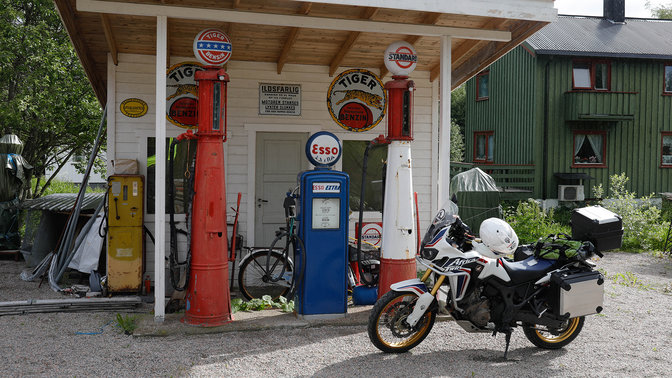 Moto estacionada numa estação de serviço numa estrada com pouco movimento.