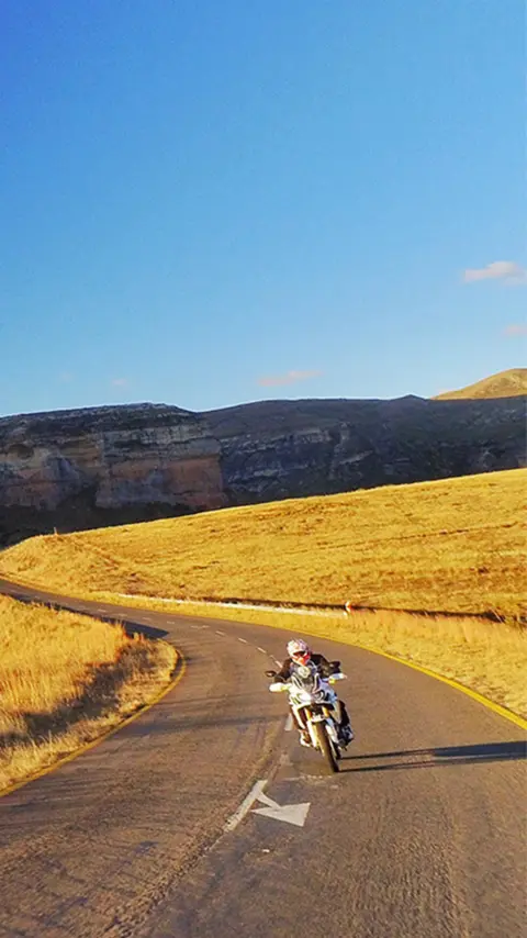 Motocykel Honda Africa Twin pri jazde popri úchvatných fjordoch a zasnežených horách v Nórsku.