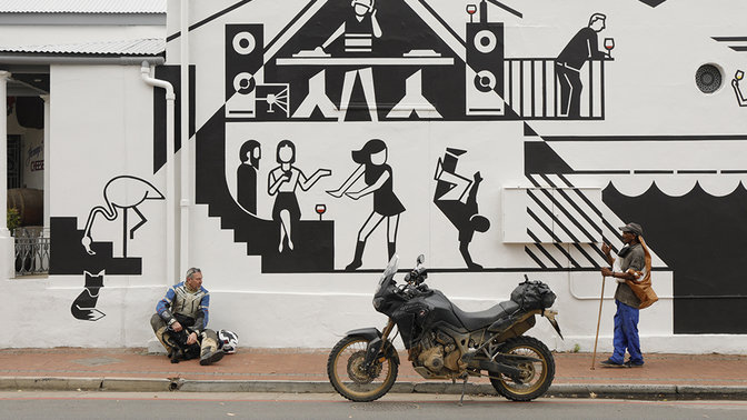 Rider parked up sitting next to a wall of street art.