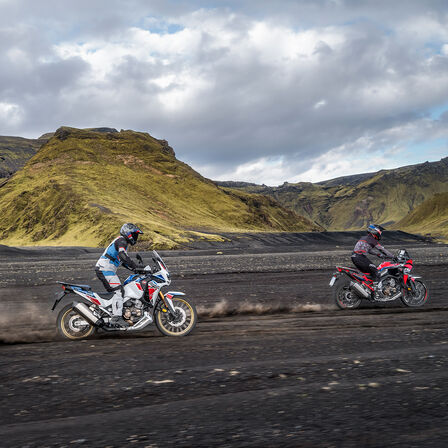 Dva jezdci na motocyklu Honda Africa Twin při jízdě v terénu.